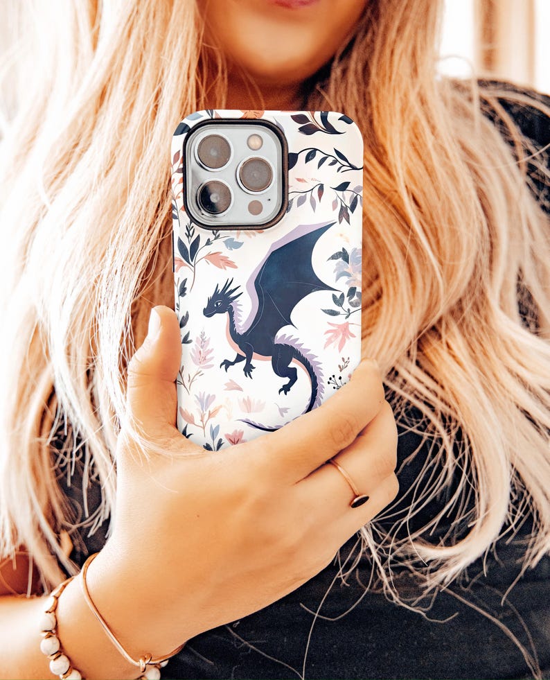 May include: A white phone case with a floral pattern and a black dragon design.