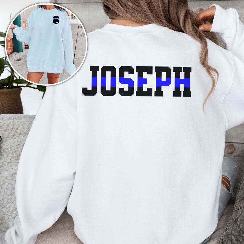 K&ouml;nnte beinhalten: Wei&szlig;er Pullover mit einem blauen Streifen und dem Namen "JOSEPH" auf der R&uuml;ckseite.