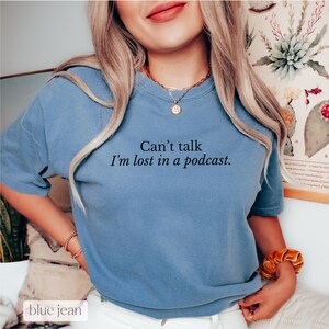 May include: A blue t-shirt with the text "Can't talk I'm lost in a podcast."