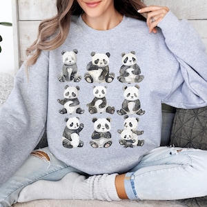 May include: A gray sweatshirt with a watercolor design of 12 pandas in different poses. The pandas are black and white with a light gray background.