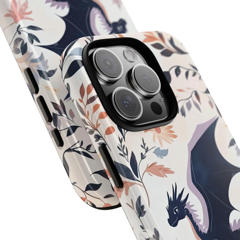 May include: A white phone case with a floral pattern and a black dragon design. The case has a camera lens cutout and a black border.
