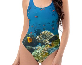 May include: A blue swimsuit with a colorful underwater scene featuring coral reefs and fish. The swimsuit has a scoop neck and a racerback style.