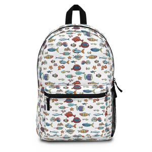 Puede incluir: Mochila blanca con un estampado de peces coloridos. La mochila tiene un asa superior negra, un bolsillo frontal con cremallera negra y un bolsillo lateral de malla. Los peces son de varios colores, incluyendo rojo, azul, amarillo y verde.
