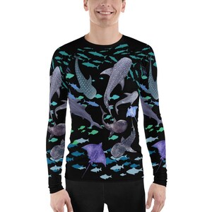 Op de afbeelding: Een zwart shirt met lange mouwen met een kleurrijke print van verschillende vissen, waaronder haaien, roggen en kleinere vissen. De print is in aquarelstijl en heeft tinten blauw, groen en paars.
