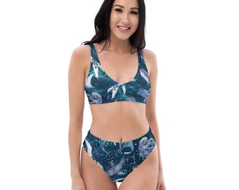 May include: A two-piece swimsuit with a dark blue aquatic design featuring whales, jellyfish, and other marine life. The top has a scoop neck and the high-waisted bottoms offer full coverage. The swimwear is designed for comfort and style.