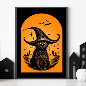 May include: A framed Halloween-themed art print featuring a black cat wearing a witch's hat. The cat is set against an orange background with bats, stars, and a silhouette of a town. The artwork is in black and orange.