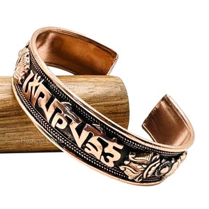 Peut inclure: Bracelet en cuivre avec un mantra tibétain gravé. Le mantra est en noir et le bracelet est de couleur or rose.