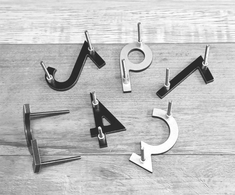 Pu&ograve; includere: Un set di sei numeri civici in metallo, tra cui i numeri 1, 2, 3, 4, 5 e 7. I numeri sono neri e argentati e hanno un design moderno e minimalista.