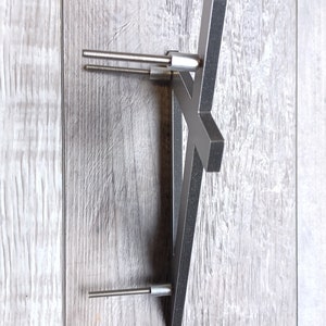 May include: A silver metal shelf bracket with two screws attached to a light gray wood surface.