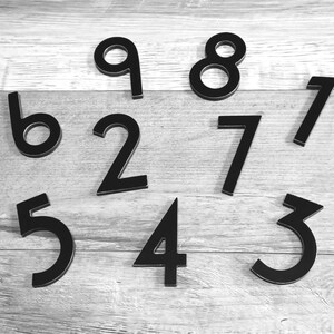 Pu&ograve; includere: I numeri neri da 1 a 9 sono sparsi su una superficie di legno chiaro.