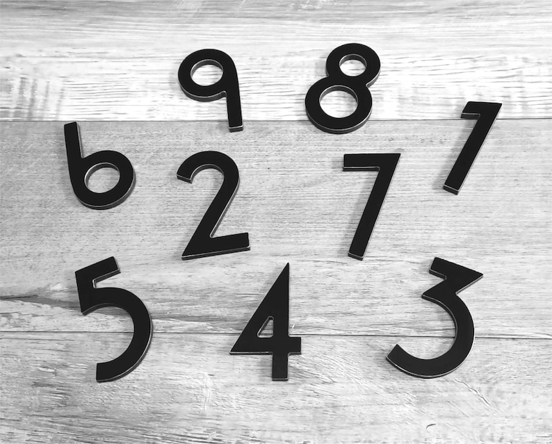 Pu&ograve; includere: I numeri neri da 1 a 9 sono sparsi su una superficie di legno chiaro.