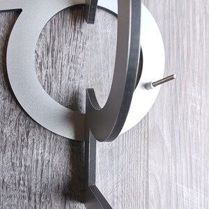 May include: A silver metal house number with a black metal bracket. The number is a "C" and is attached to the bracket with a screw.