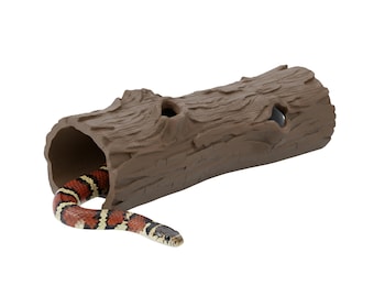 May include: A brown, log-shaped reptile hideaway with three holes. A colorful snake with red, black, and white markings is partially visible, emerging from the hideaway. The reptile habitat is designed to mimic a natural environment.