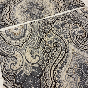 May include: Two rectangular fabric pieces featuring a complex paisley pattern in shades of slate blue, charcoal gray, cream, and tan. The intricate design consists of swirling teardrop shapes, floral motifs, and fine decorative line work.