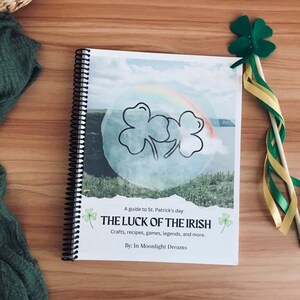Może przedstawiać: Przewodnik po Dniu Świętego Patryka zatytułowany "The Luck of the Irish". Okładka książki przedstawia zieloną koniczynę, tęczę i krajobraz z akwenem wodnym. Książka jest spiralnie oprawiona i ma białe tło.