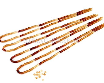 May include: Five strands of brown, orange, and white gemstone beads. The beads are small and round. There are also a few loose beads on the white background.