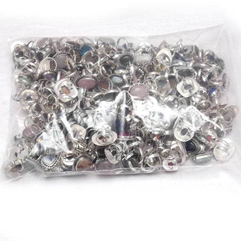 Puede incluir: Una bolsa de pl&aacute;stico transparente llena de numerosos anillos plateados. Los anillos presentan varias engastes de piedras preciosas en una variedad de formas y colores, incluyendo piedras rosas, azules y transparentes. Los anillos son de diferentes tama&ntilde;os y estilos.