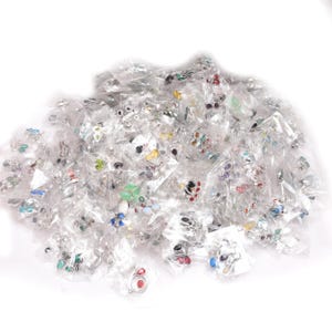 Puede incluir: Una colecci&oacute;n de anillos variados, cada uno empaquetado individualmente en pl&aacute;stico transparente. Los anillos presentan diversos dise&ntilde;os, incluyendo piedras preciosas coloridas y intrincados trabajos en metal. La imagen muestra una variedad de estilos y colores.