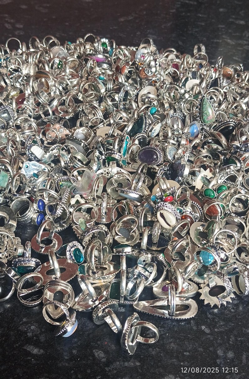 Puede incluir: Una gran colecci&oacute;n de anillos de plata con diversos engastes de piedras preciosas, incluyendo turquesas, amatistas y piedras claras. Los anillos se exhiben en un mont&oacute;n, mostrando una variedad de dise&ntilde;os y tama&ntilde;os. La imagen captura el brillo del metal y los colores de las piedras.