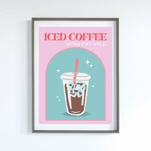 Op de afbeelding: Een roze en blauwe poster met de tekst "ICED COFFEE WITH OAT MILK" in rode en bruine letters. Een cartoonillustratie van een doorzichtig plastic bekertje met een bruine drank en ijsblokjes, en een roze rietje zit in het bekertje. Er zijn witte sterren rond het bekertje.