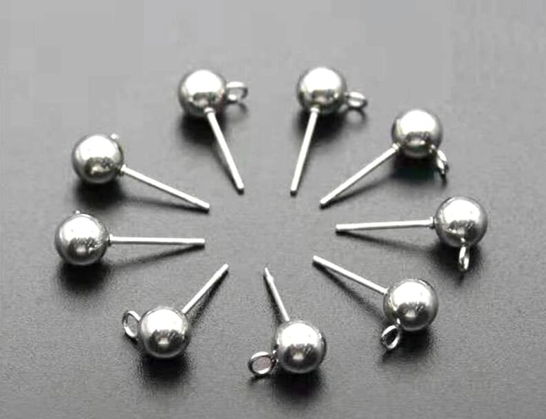 Op de afbeelding: Tien zilveren oorbelpennen met ronde bolvormige toppen. De pennen zijn ongeveer 2,5 cm lang.
