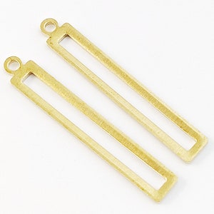 May include: Two gold-toned metal rectangular frame pendants with a loop at the top for hanging.