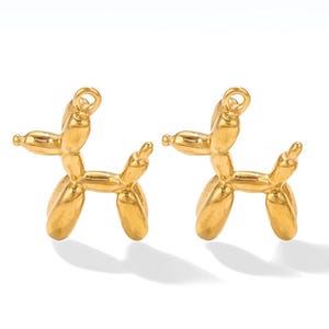 May include: Two gold-coloured balloon animal charms in the shape of a dog. The charms are small and detailed.