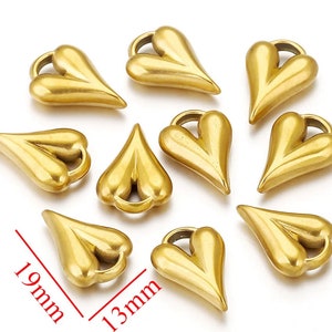May include: Ten gold-colored metal heart-shaped charms with a loop at the top. The charms are approximately 1.3 inches long and 0.9 inches wide.