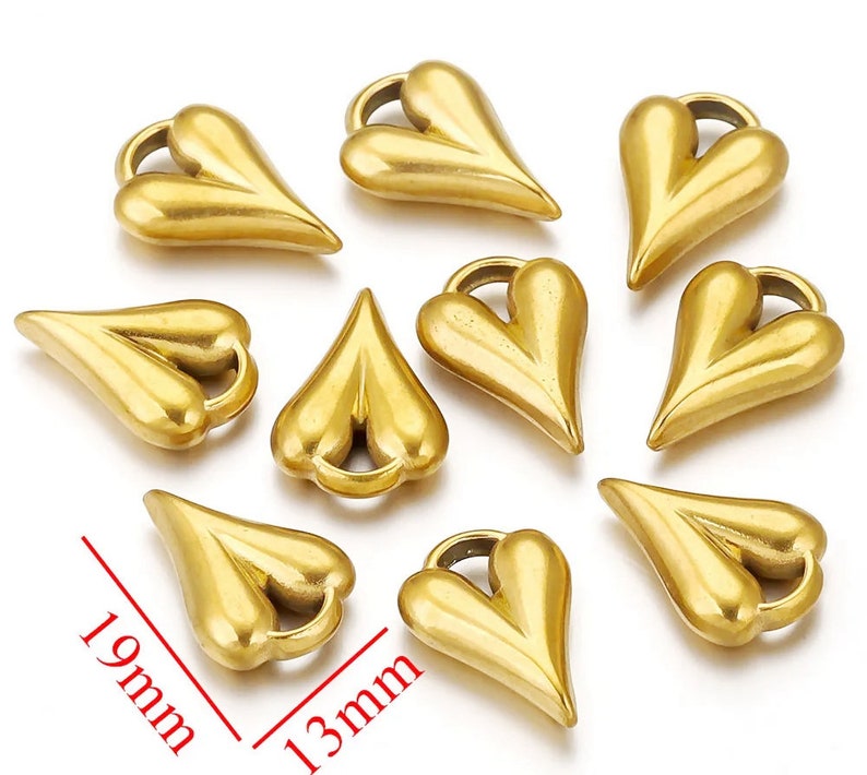 May include: Ten gold-colored metal heart-shaped charms with a loop at the top. The charms are approximately 1.3 inches long and 0.9 inches wide.