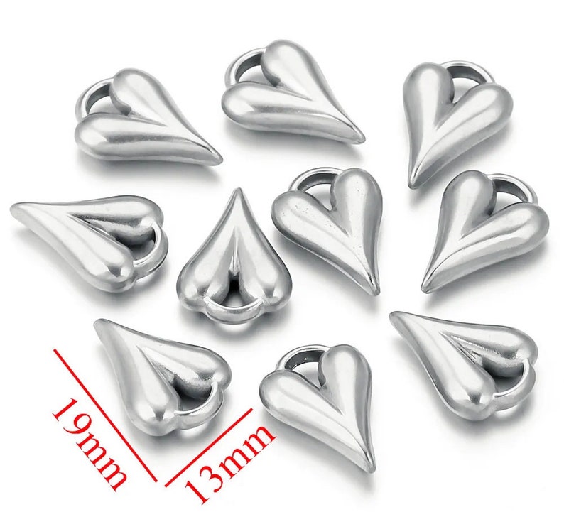 May include: Ten silver heart-shaped charms with a loop at the top. The charms are 19 mm long and 13 mm wide.