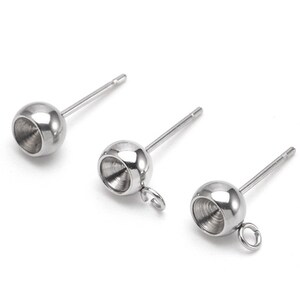 May include: Three silver earring posts with a round ball at the top. The ball has a small hole in the center. The post on the right has a small loop at the bottom.