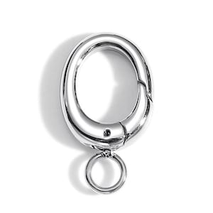 May include: A shiny, silver-colored oval-shaped clasp with a hinged opening and a small, attached ring. The clasp is designed to open and close, likely for securing items. The metal has a polished, reflective surface.