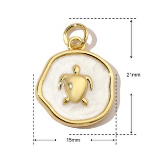K&ouml;nnte beinhalten: Goldfarbener Anh&auml;nger mit einem wei&szlig;en Emaille-Schildkr&ouml;ten-Design. Der Anh&auml;nger ist 15 mm breit und 21 mm hoch.