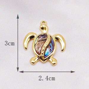 May include: Gold-tone turtle pendant with a shell made of iridescent abalone. The pendant measures 2.4 cm wide and 3 cm tall.