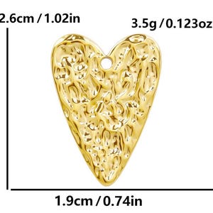 May include: A gold-colored heart-shaped charm with a textured surface. The charm measures 2.6 cm by 1.9 cm and weighs 3.5 grams.
