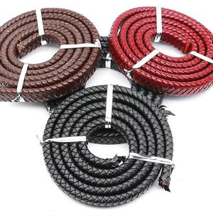 Può includere: Tre cordoni in pelle di diversi colori: marrone, rosso e nero. I cordoni sono intrecciati e hanno una superficie testurizzata.