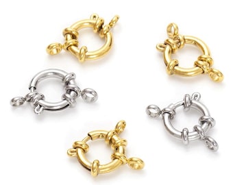 May include: Five silver and gold metal clasps with a round ring and a loop on each side. The clasps are used for jewelry making.