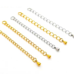 May include: Four gold and silver chain extenders with lobster clasps and teardrop-shaped ends. The extenders are arranged in a row on a white background.