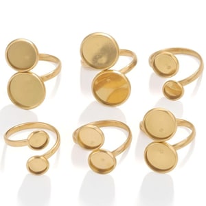 May include: Six gold-toned rings with round, bezel-set settings. The rings are designed to hold cabochons or other flat-backed stones.