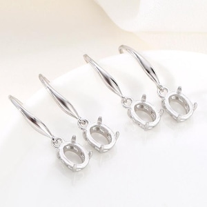 May include: Three silver oval-shaped earring blanks with a hook closure. The blanks are ready to be set with stones or other embellishments.