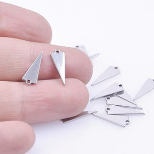 May include: A group of silver triangle charms with a hole at the top for attaching to jewelry or other crafts.
