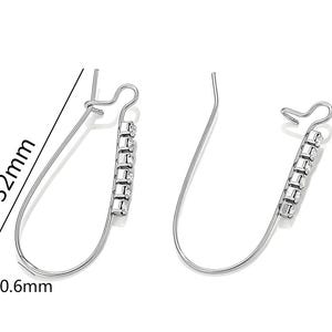 Könnte beinhalten: Ein Paar silberfarbene Ohrringe, jeweils 3,2 cm lang und 0,6 mm dick. Sie verfügen über eine Reihe kleiner, klarer Edelsteine. Das Design umfasst einen gebogenen Draht und einen Haken für durchbohrte Ohren.