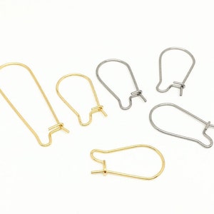 May include: Five earring hooks, two gold and three silver, are displayed on a white surface. The hooks are all different sizes and shapes.