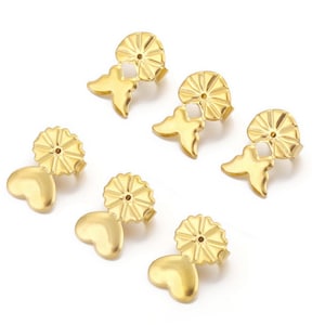 May include: Six gold-tone earring backs with butterfly and heart designs. The backs are designed to be used with post earrings.