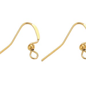 Può includere: Una coppia di monachelle per orecchini in metallo color oro, ciascuna caratterizzata da un design a filo curvo, una piccola perlina decorativa e un occhiello circolare alla base per fissare componenti di gioielleria. Finitura liscia.