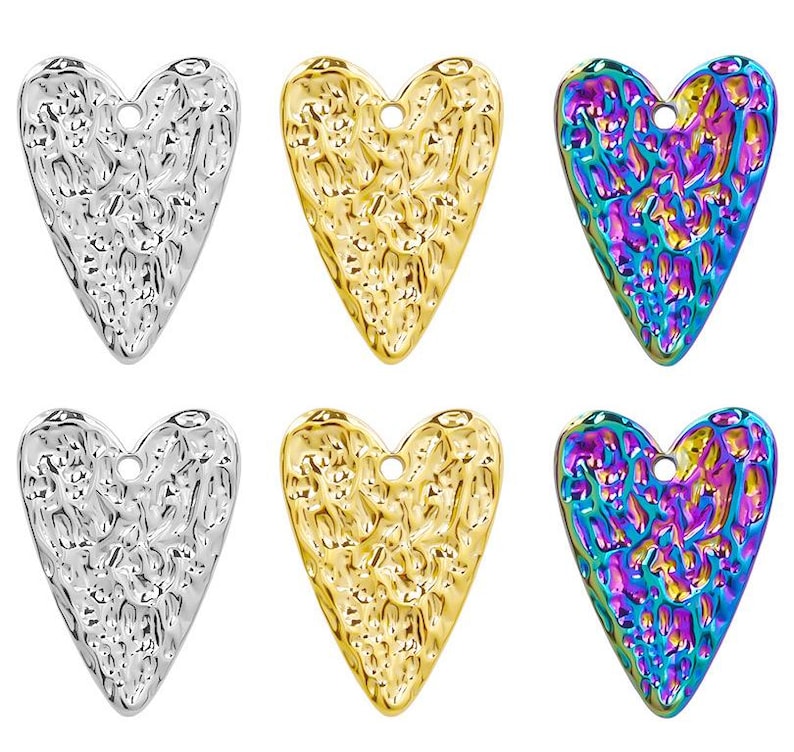 May include: Six heart-shaped metal charms in three different finishes: silver, gold, and iridescent. Each charm has a textured surface and a small hole at the top for attaching to jewelry or other crafts.