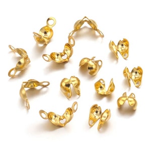 Puede incluir: Un conjunto de 14 cuentas de crimpado de metal dorado, utilizadas para la elaboración de joyas. Las cuentas están diseñadas para ser crimpadas en un cordón o cuerda para asegurar los nudos y crear un acabado profesional.