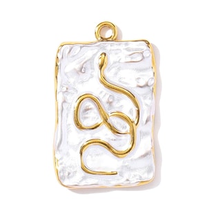 Op de afbeelding: Een rechthoekige hanger met een goudkleurig frame en een witte, getextureerde achtergrond. Een goudkleurig slangenontwerp is gecentreerd op de hanger. De hanger heeft een kleine lus aan de bovenkant om aan een ketting te bevestigen.