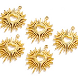 May include: Five gold-colored metal charms shaped like a sunburst with a heart cut out in the center.