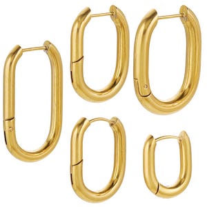 May include: Several gold-coloured oval hoop earrings of different sizes. The earrings have a polished finish and a hinged clasp. The image displays the earrings against a white background, emphasising their shape and design.